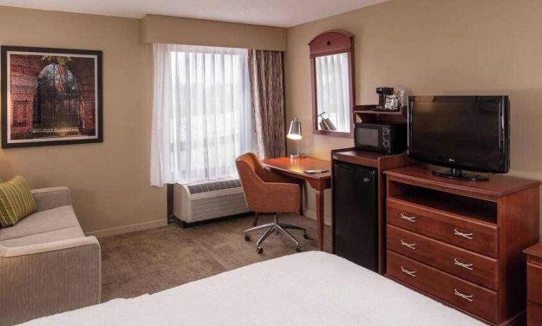 King size bed, sofa and desk in a hotel room at the Hampton Inn Columbia Northeast-Fort Jackson Area, SC.