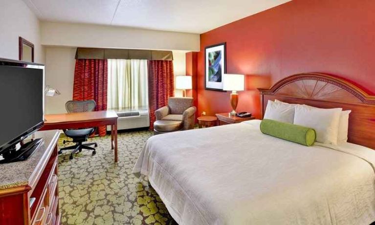 beautiful king suite with TV, work desk, and lounge area at Hilton Garden Inn Chicago/Midway Airport.