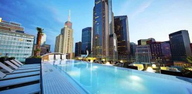 Relaxing outdoor pool with skyline view at the Statler Dallas, Curio Collection by Hilton.