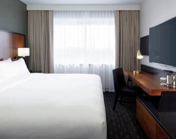 1 king bed room with tv and chair at the DoubleTree by Hilton Montreal Airport