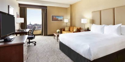 King room with 1 king bed, desk,chair and view of downtown at the Hilton Saint John