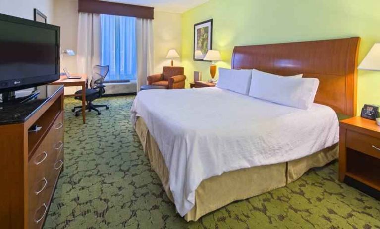 King size bed, TV screen and desk in a hotel room at the Hilton Garden Inn Tallahassee Central.