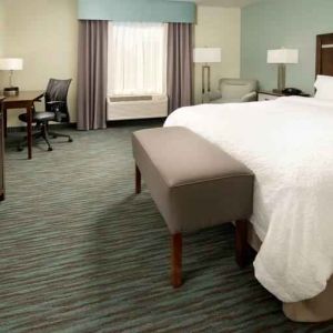 Comfortable king bedroom with TV screen and desk at the Hampton Inn & Suites Schererville.