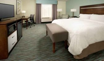 Comfortable king bedroom with TV screen and desk at the Hampton Inn & Suites Schererville.