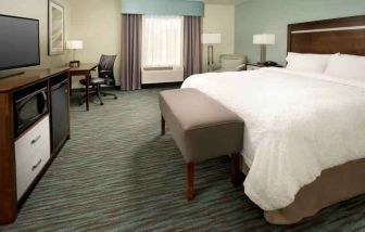 Comfortable king bedroom with TV screen and desk at the Hampton Inn & Suites Schererville.