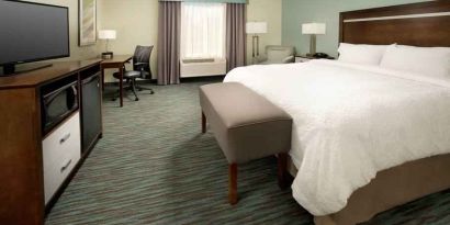 Comfortable king bedroom with TV screen and desk at the Hampton Inn & Suites Schererville.