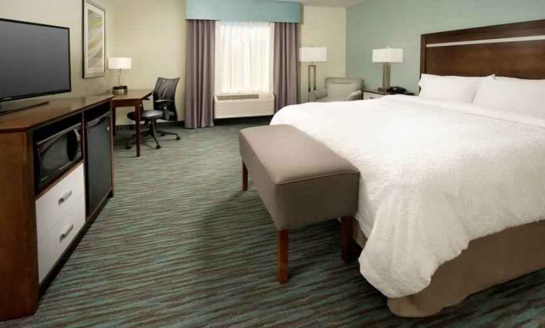 Comfortable king bedroom with TV screen and desk at the Hampton Inn & Suites Schererville.