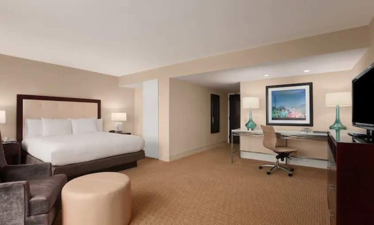 King size bed, desk and sofa in a spacious hotel room at the at the Hilton Miami Airport Blue Lagoon.