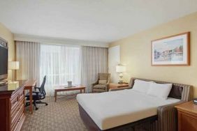 King size bed, desk and TV screen in a hotel room at the Hilton Seattle Airport & Conference Center.