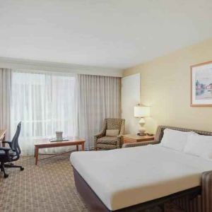 King size bed, desk and TV screen in a hotel room at the Hilton Seattle Airport & Conference Center.