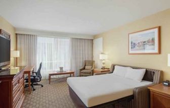 King size bed, desk and TV screen in a hotel room at the Hilton Seattle Airport & Conference Center.