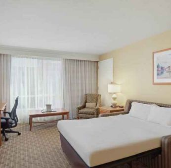 King size bed, desk and TV screen in a hotel room at the Hilton Seattle Airport & Conference Center.