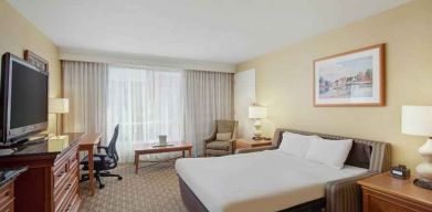 King size bed, desk and TV screen in a hotel room at the Hilton Seattle Airport & Conference Center.