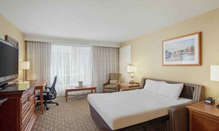 King size bed, desk and TV screen in a hotel room at the Hilton Seattle Airport & Conference Center.