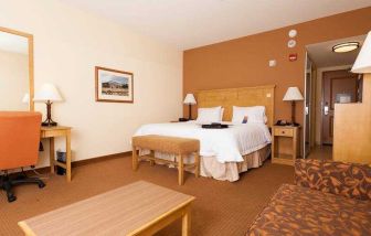 Spacious king suite with sofa and desk at the Hampton Inn & Suites Riverton, WY.