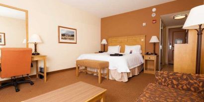 Spacious king suite with sofa and desk at the Hampton Inn & Suites Riverton, WY.