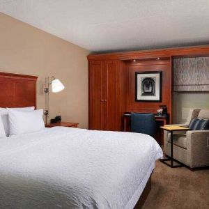 Comfortable king room with TV screen, sofa and desk at the Hampton Inn Ann Arbor South.