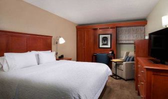 Comfortable king room with TV screen, sofa and desk at the Hampton Inn Ann Arbor South.