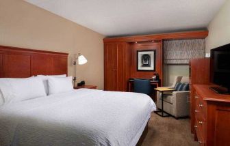 Comfortable king room with TV screen, sofa and desk at the Hampton Inn Ann Arbor South.