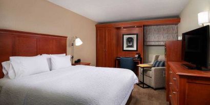 Comfortable king room with TV screen, sofa and desk at the Hampton Inn Ann Arbor South.