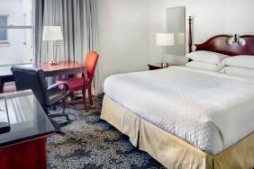 King size bed, desk and TV screen in a hotel room at the Embassy Suites by Hilton Portland-Downtown.