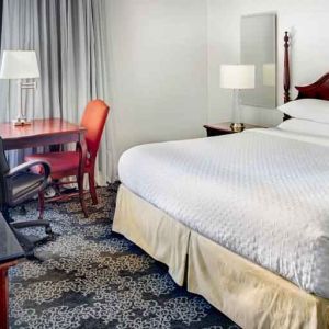 King size bed, desk and TV screen in a hotel room at the Embassy Suites by Hilton Portland-Downtown.