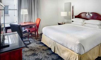 King size bed, desk and TV screen in a hotel room at the Embassy Suites by Hilton Portland-Downtown.