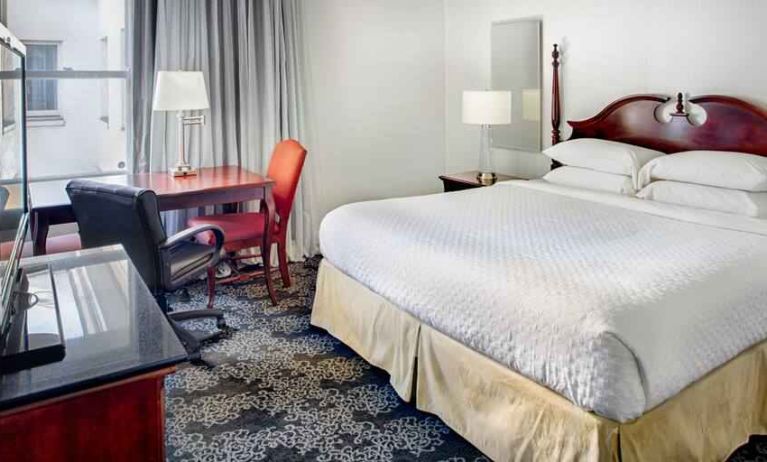 King size bed, desk and TV screen in a hotel room at the Embassy Suites by Hilton Portland-Downtown.