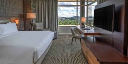 Executive king bedroom with desk, window and TV screen at the Hilton Franklin Cool Springs.