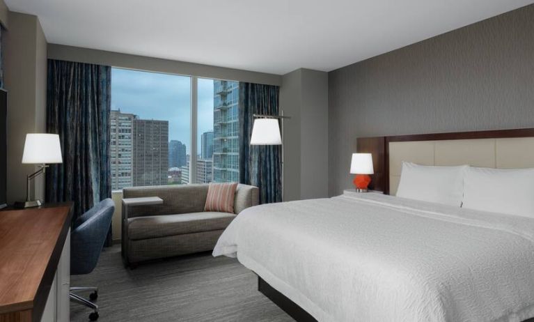 Comfortable king suite with desk, sofa and window at the Hampton Inn Chicago McCormick Place.