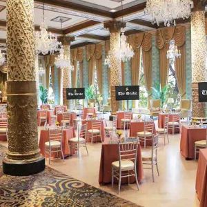 Elegant event room with big windows, lovely chandeliers and intricate pillars at The Drake.