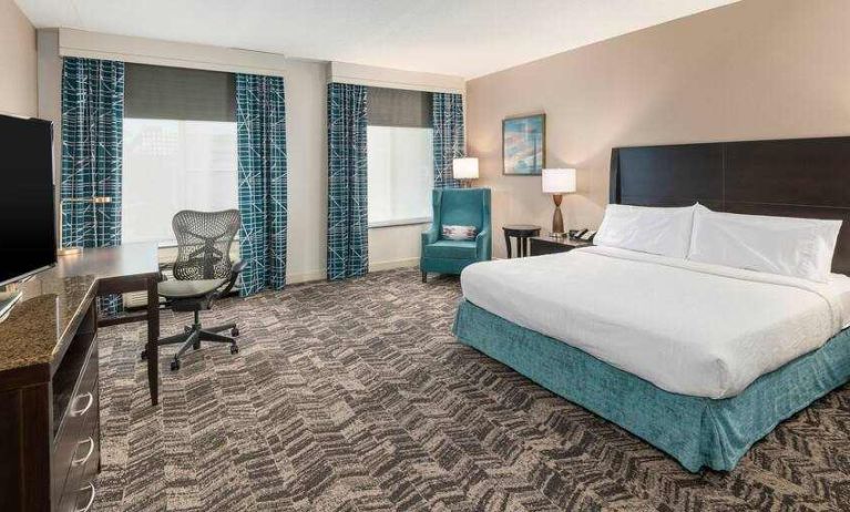 King size bed, sofa and desk in a hotel room at the Hilton Garden Inn Silver Spring White Oak.