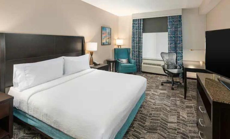 Comfortable hotel guestroom with king size bed and working station at the Hilton Garden Inn Silver Spring White Oak.