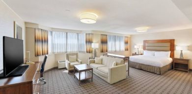 Beautiful king suite with desk, TV screen and sofa at the Hilton Crystal City at Washington Reagan National Airport.