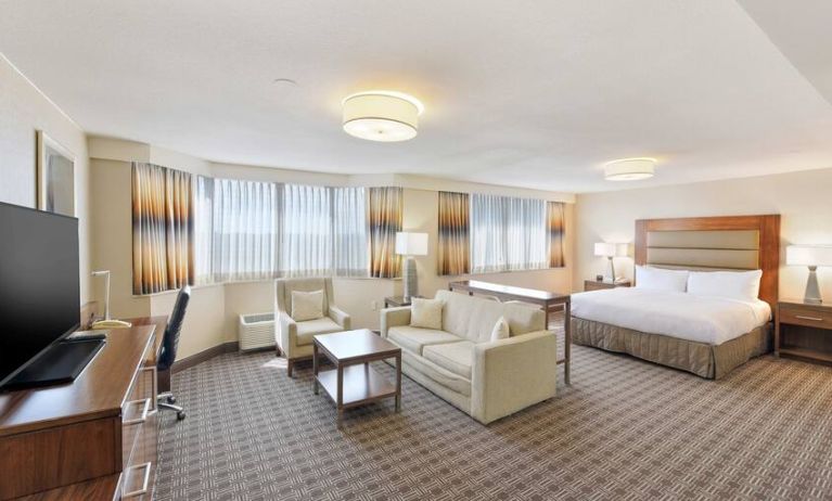 Beautiful king suite with desk, TV screen and sofa at the Hilton Crystal City at Washington Reagan National Airport.