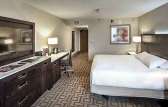 TV screen, desk and sofa in a king suite at the Hilton Sacramento-Arden West.