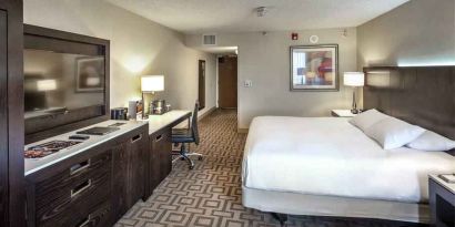 TV screen, desk and sofa in a king suite at the Hilton Sacramento-Arden West.