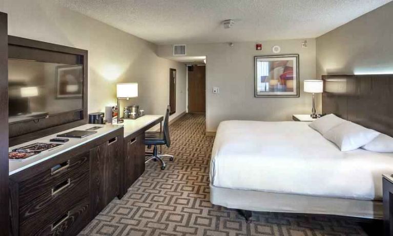 TV screen, desk and sofa in a king suite at the Hilton Sacramento-Arden West.