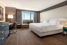 King guestroom with TV screen, desk and window at the Hilton Baltimore BWI Airport.