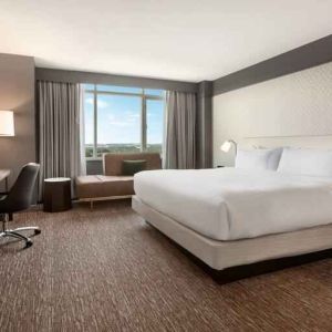 King guestroom with TV screen, desk and window at the Hilton Baltimore BWI Airport.