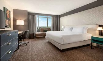 King guestroom with TV screen, desk and window at the Hilton Baltimore BWI Airport.