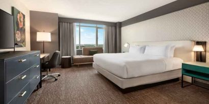 King guestroom with TV screen, desk and window at the Hilton Baltimore BWI Airport.