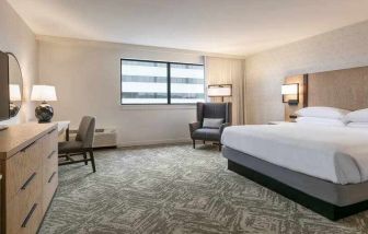 King size bed, TV screen and desk in a hotel room at the DoubleTree by Hilton Canton Downtown.