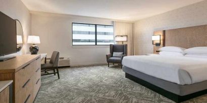 King size bed, TV screen and desk in a hotel room at the DoubleTree by Hilton Canton Downtown.