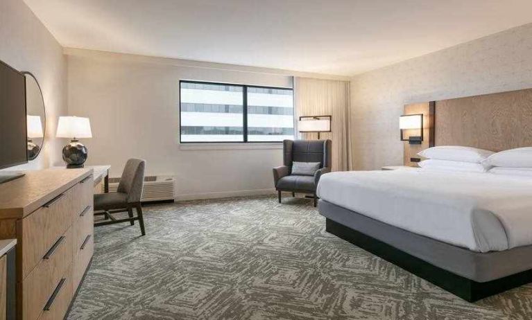 King size bed, TV screen and desk in a hotel room at the DoubleTree by Hilton Canton Downtown.