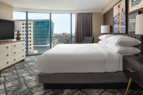 King size bed, TV screen and large window in a hotel room at the Embassy Suites by Hilton San Francisco Airport.