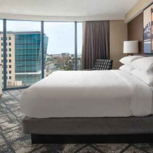 King size bed, TV screen and large window in a hotel room at the Embassy Suites by Hilton San Francisco Airport.