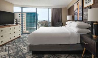 King size bed, TV screen and large window in a hotel room at the Embassy Suites by Hilton San Francisco Airport.