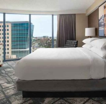 King size bed, TV screen and large window in a hotel room at the Embassy Suites by Hilton San Francisco Airport.