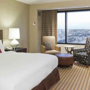 King size bed, TV screen, sofa and desk in a hotel room with window at the Hilton Omaha.